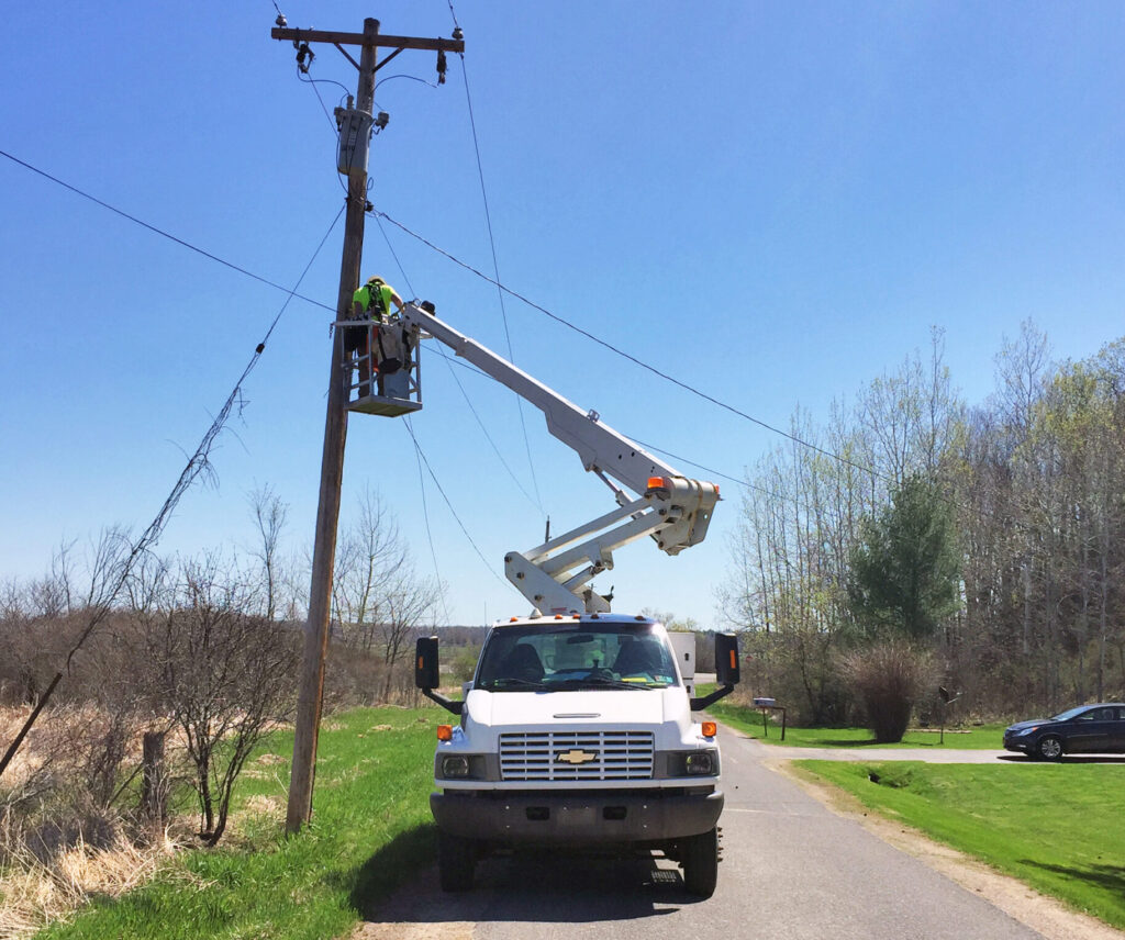 Final walkthrough of a fiber installation site with a bucket truck and cleared roadside.