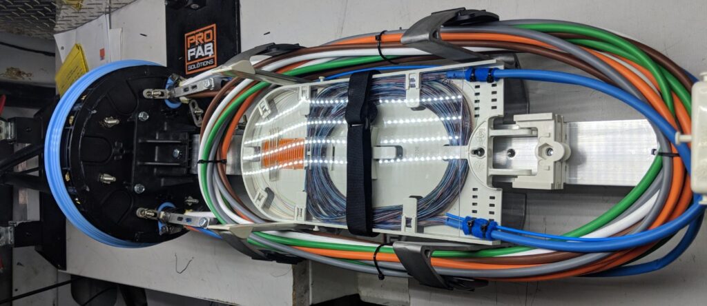 Organized fiber splice enclosure with labeled strands and structured cable routing for quality assurance testing