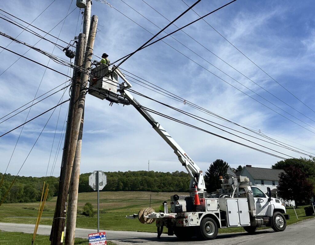 Aerial fiber technician accessing a pole with no weather delays on a dry summer day