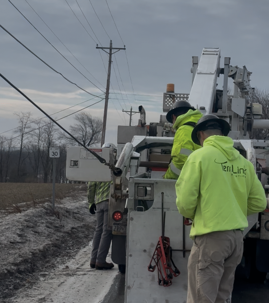 Fiber installation crew working safely near roadside barriers.